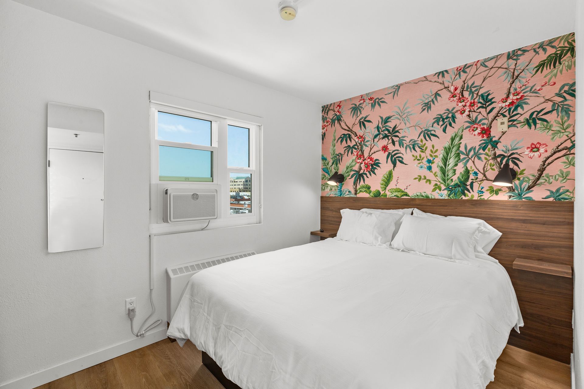 A hotel room with a king size bed and a floral wallpaper on the wall.