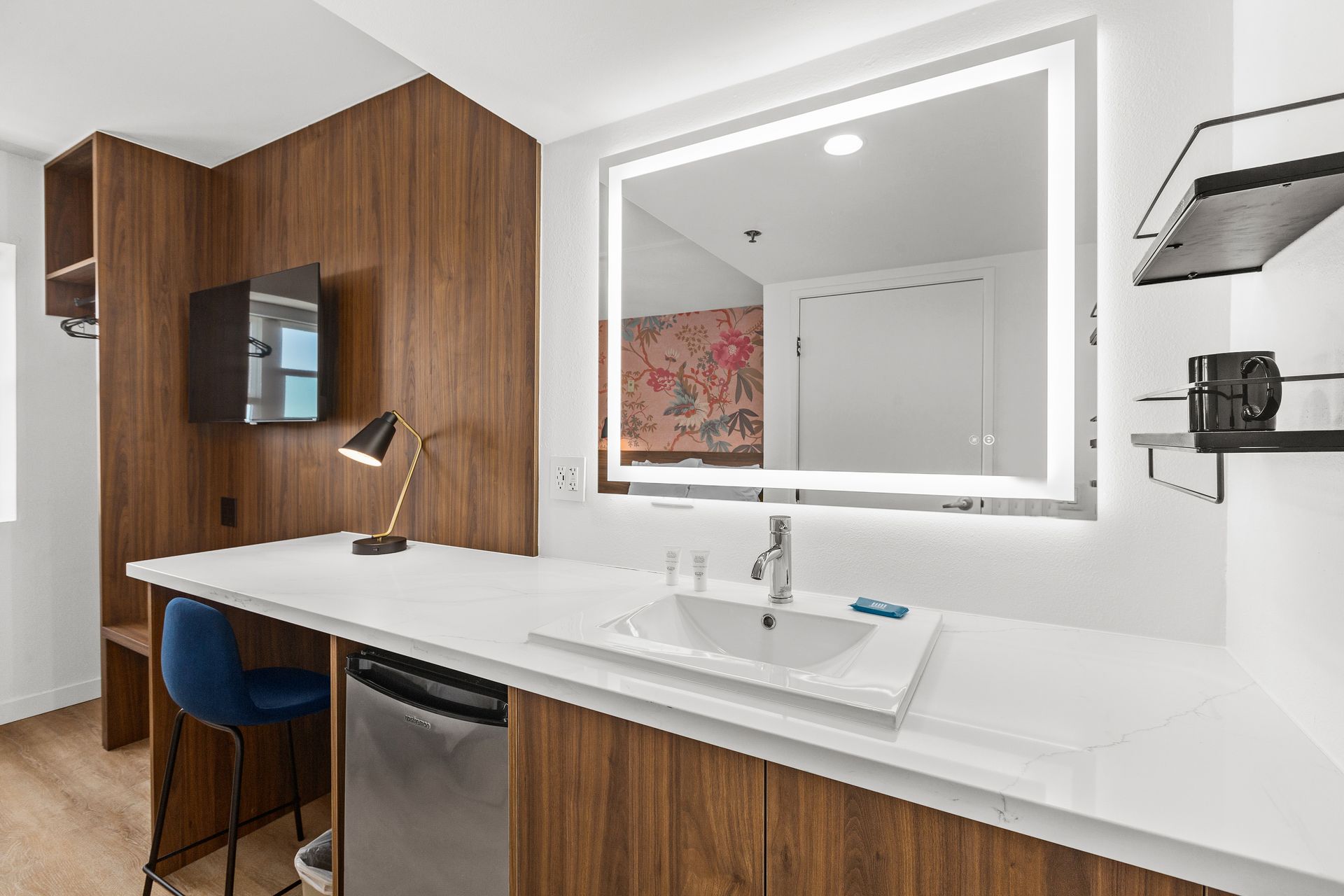 A hotel room with a sink and a large mirror.