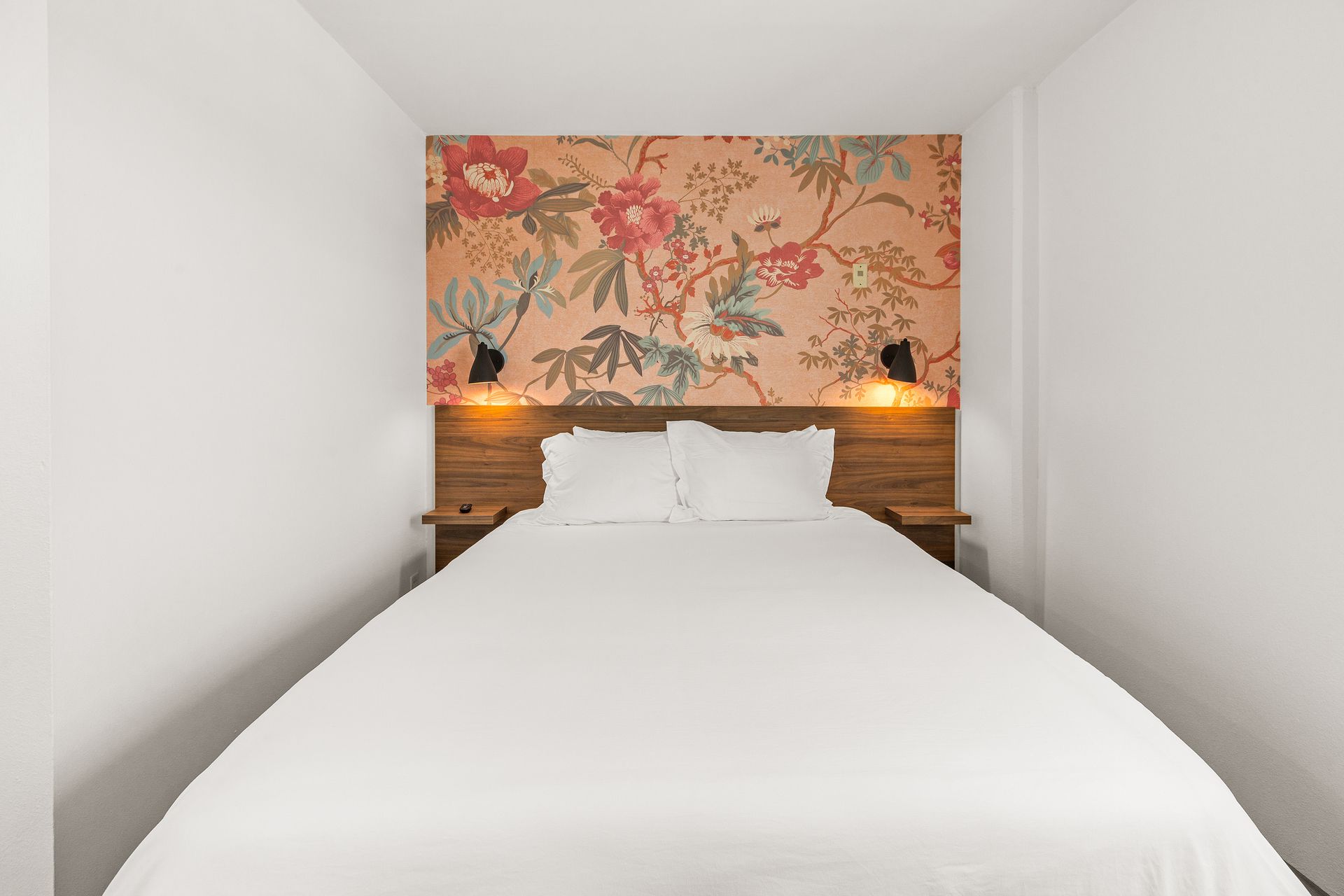 A bedroom with a bed and a floral wallpaper on the wall