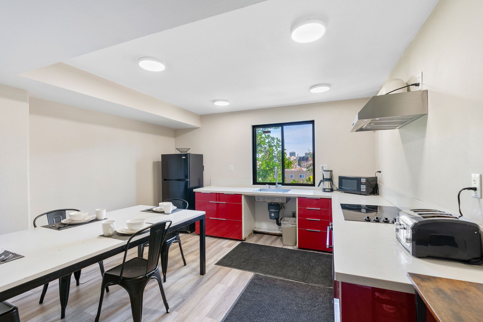 A kitchen with red cabinets , a table and chairs.