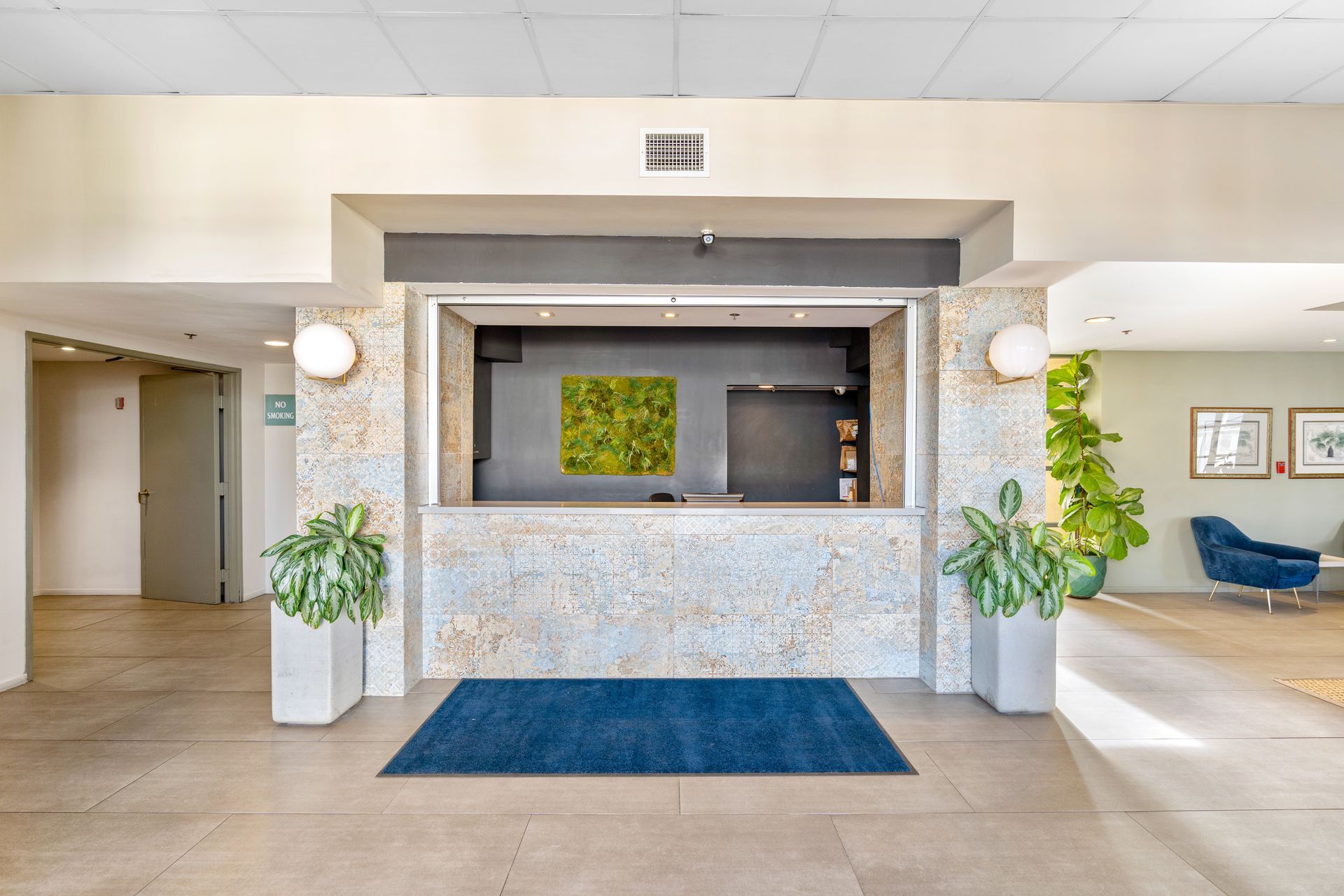 A hotel lobby with a reception desk and a blue rug