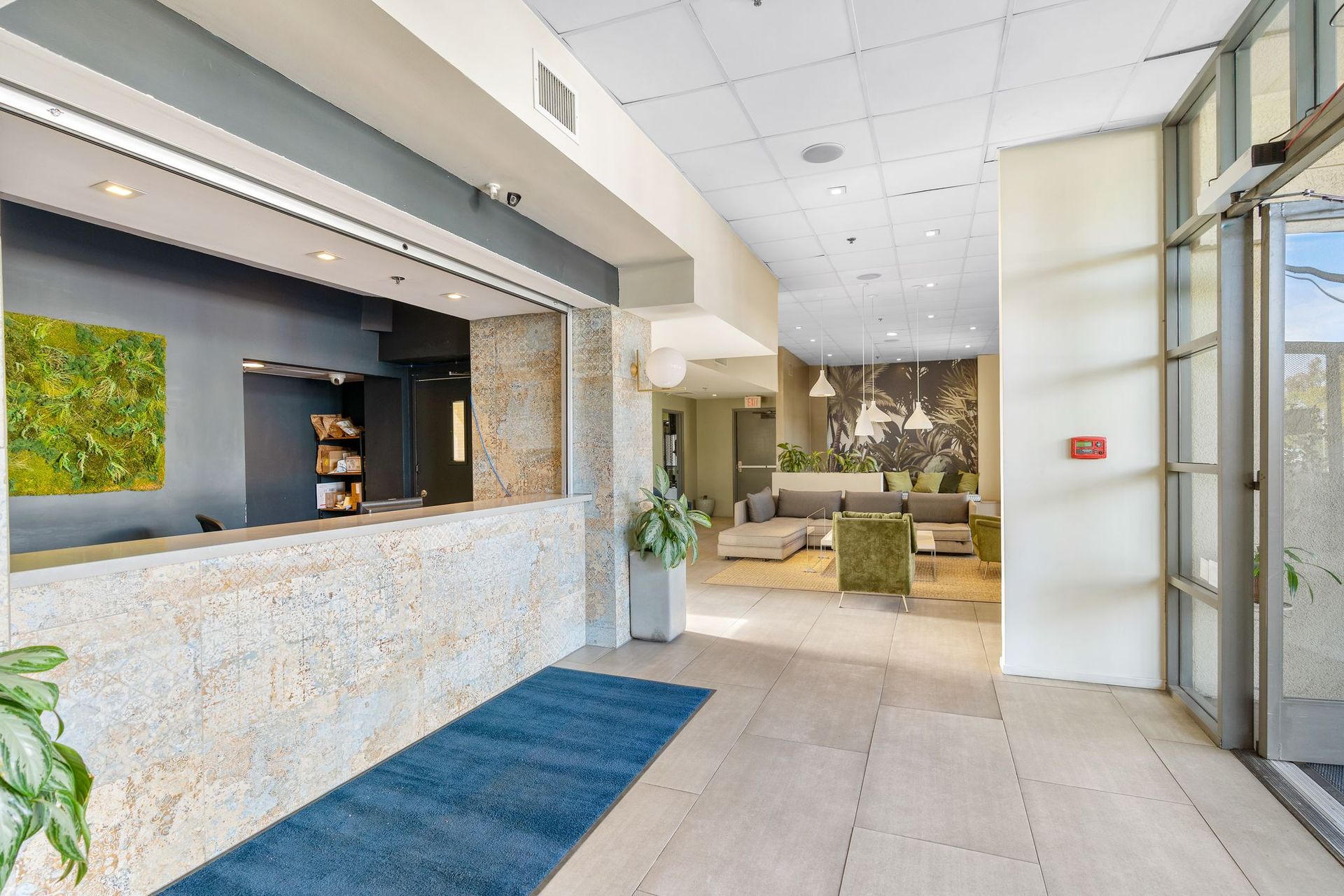 A hotel lobby with a reception desk and a blue rug.