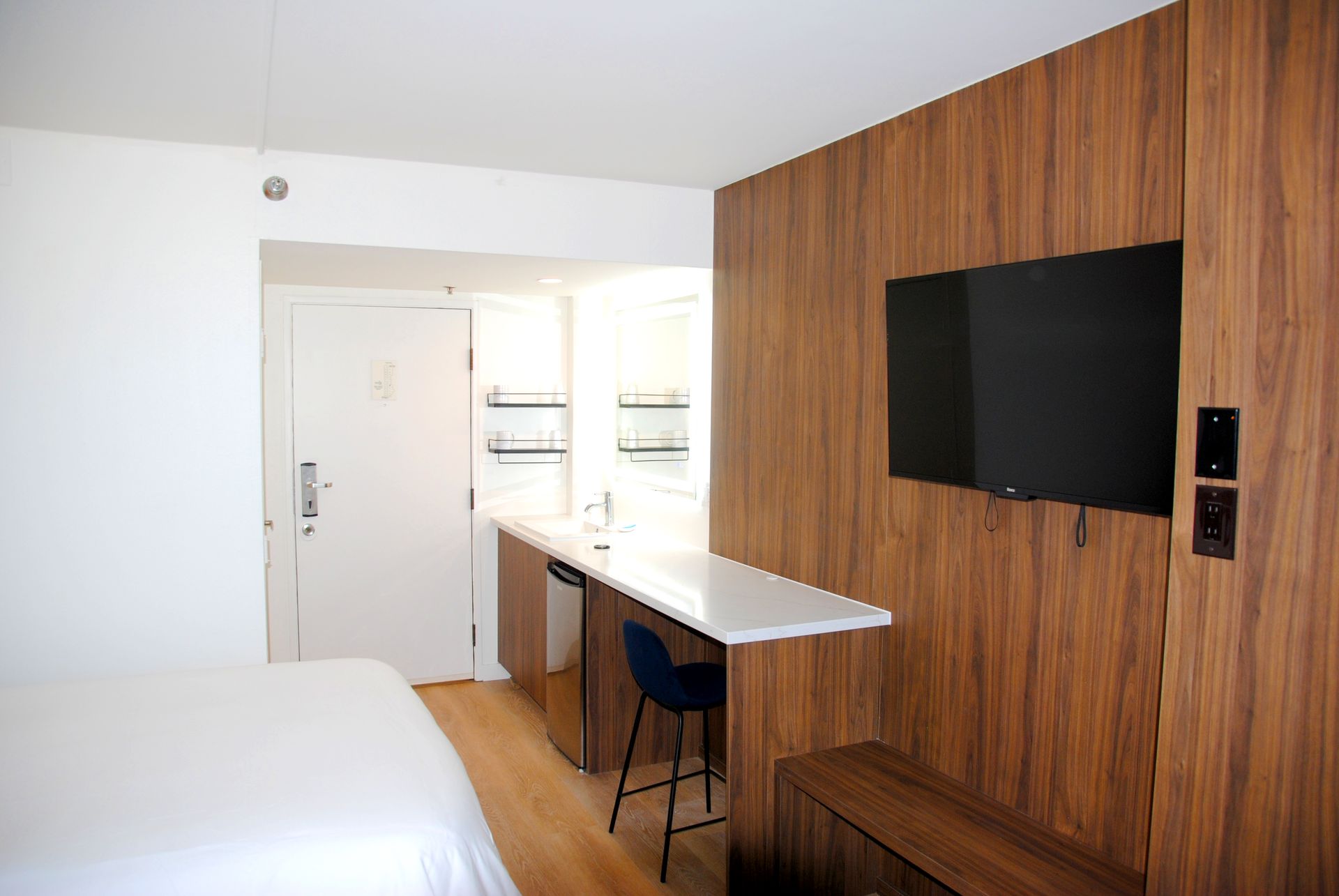 A hotel room with a bed and a flat screen tv on the wall.