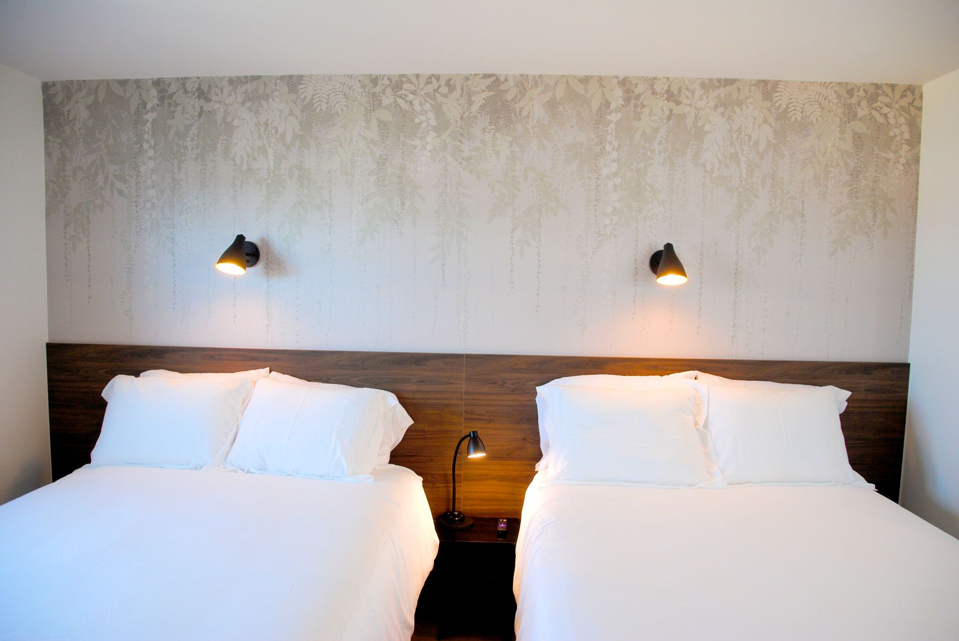 A hotel room with two beds and two lamps.