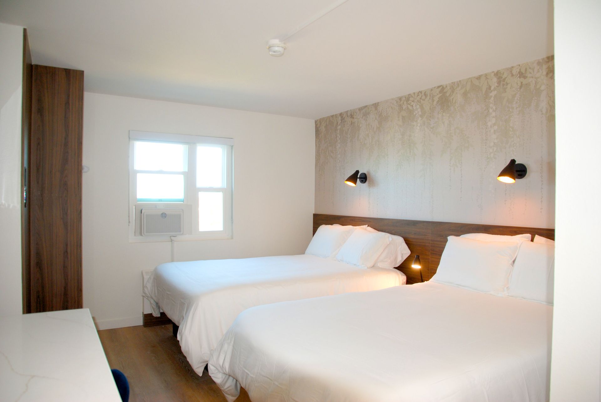 A hotel room with two beds and a window.