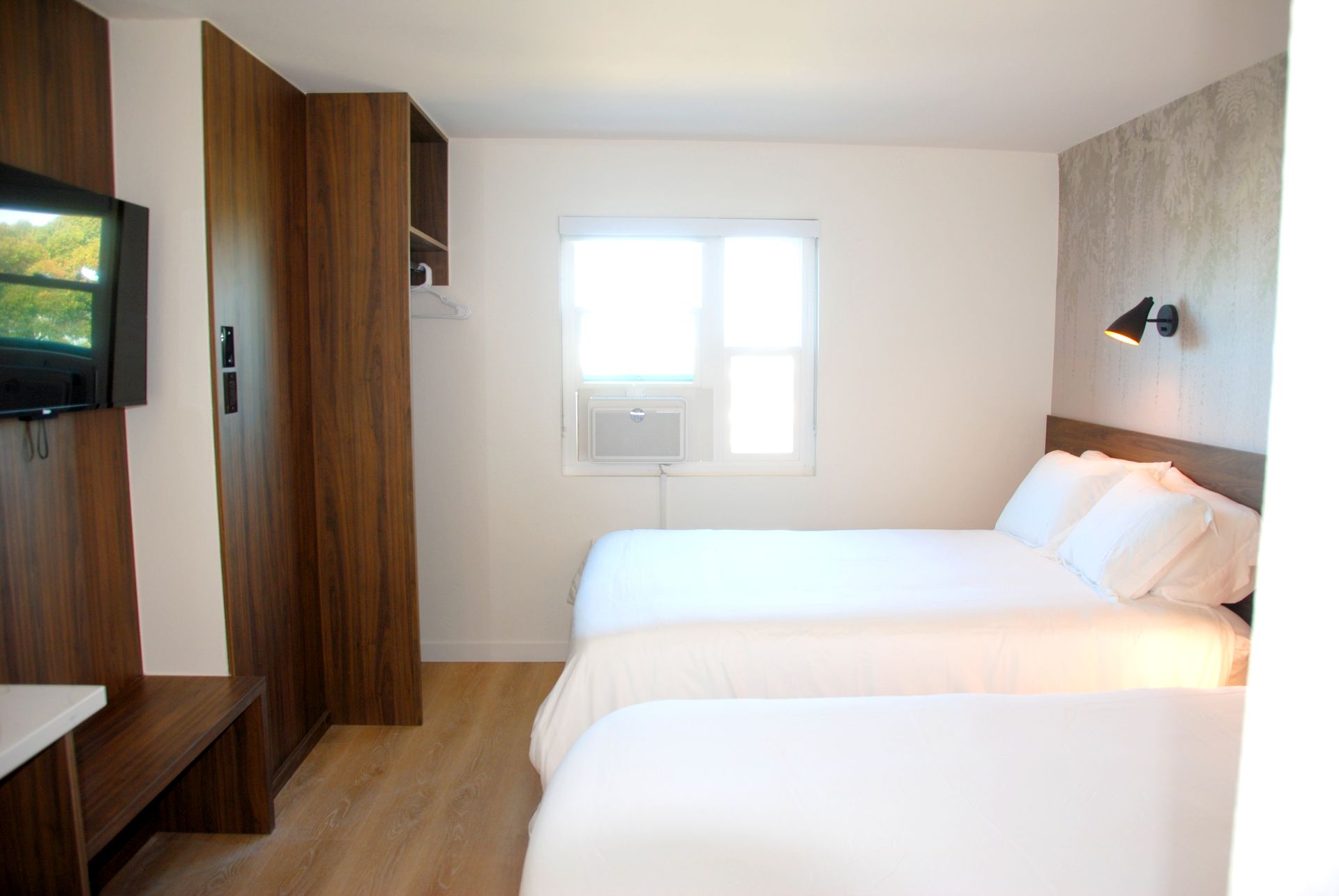 A hotel room with two beds and a flat screen tv