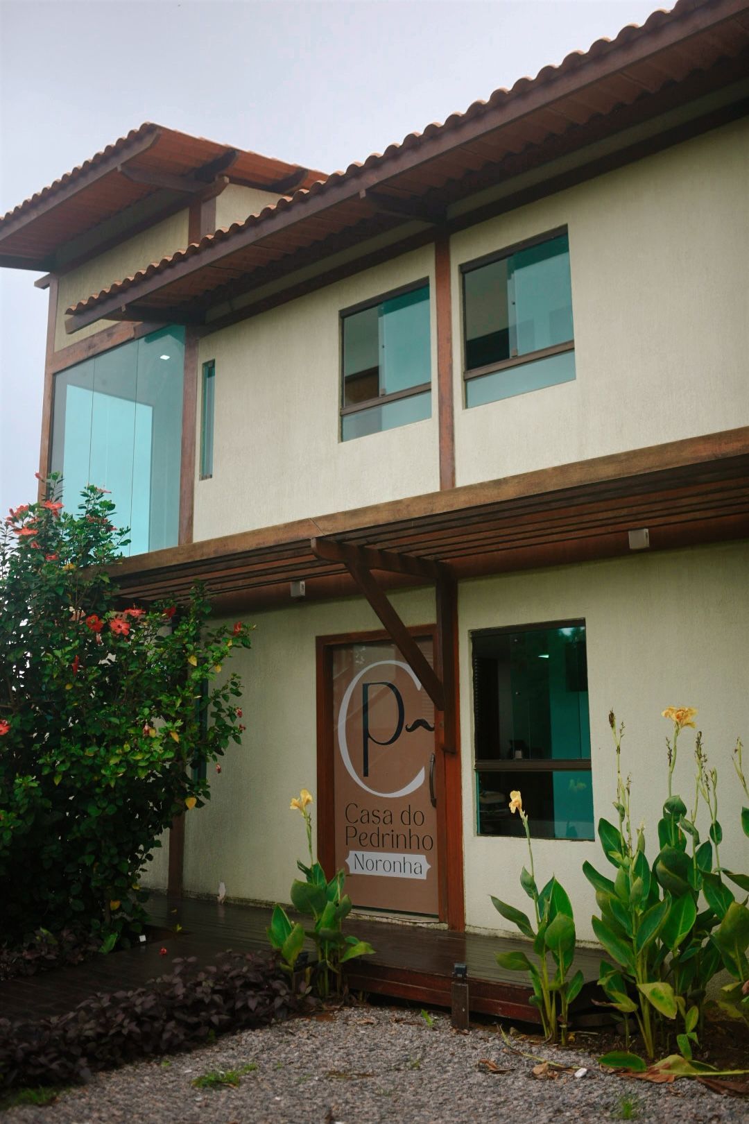 Uma casa grande com muitas janelas e uma placa que diz p. - Casa Pedrinho Noronha