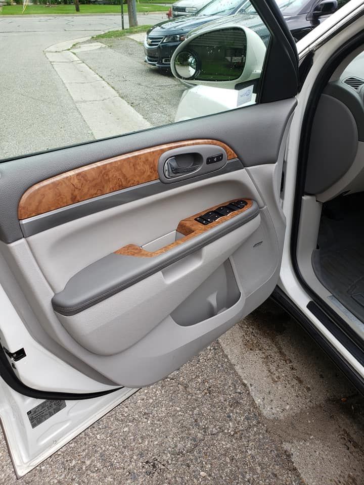 A white car with the door open is parked on the side of the road.