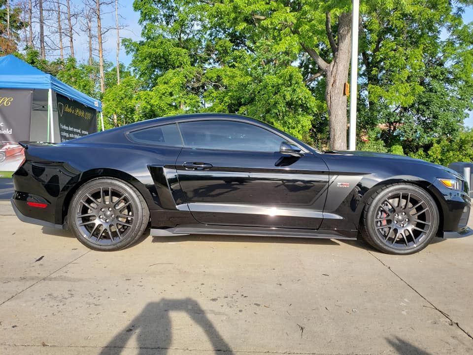 A black ford mustang is parked on the side of the road.