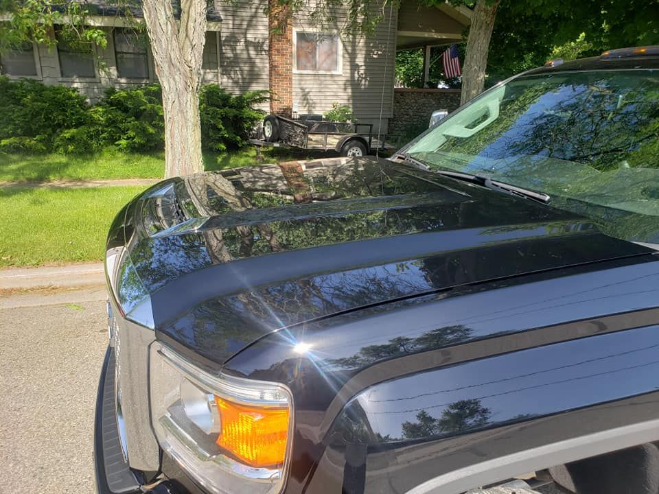 A black truck is parked on the side of the road in front of a house.