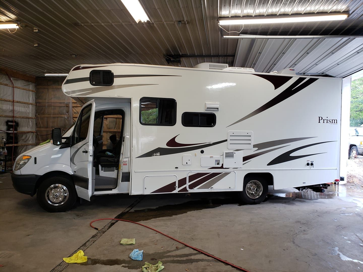 A white rv is parked in a garage with the door open.