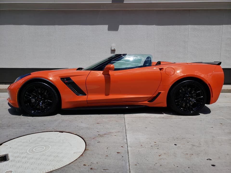 An orange sports car is parked in front of a building.