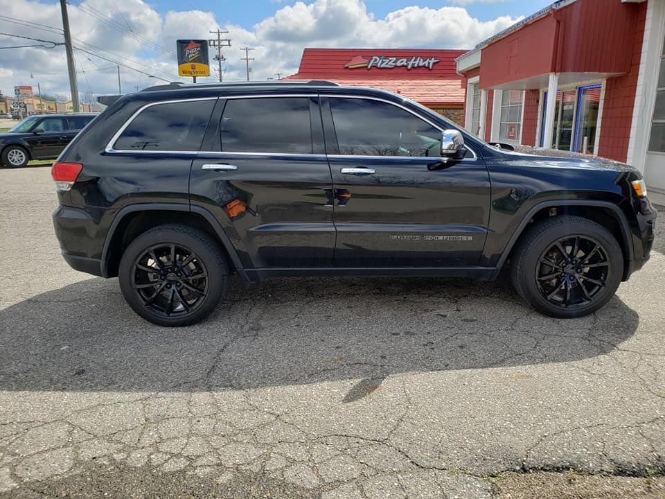 A black jeep grand cherokee is parked in front of a pizza hut.