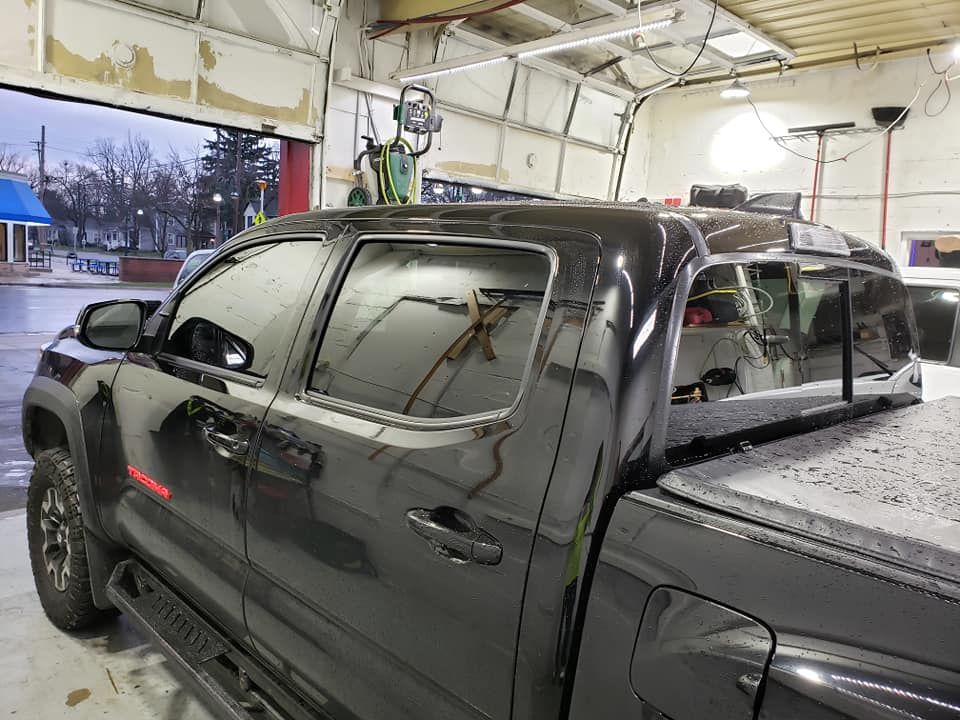 A black truck with a roof rack is parked in a garage.