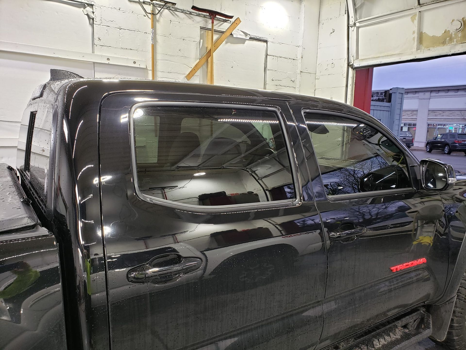 A black truck is parked in a garage next to a garage door.