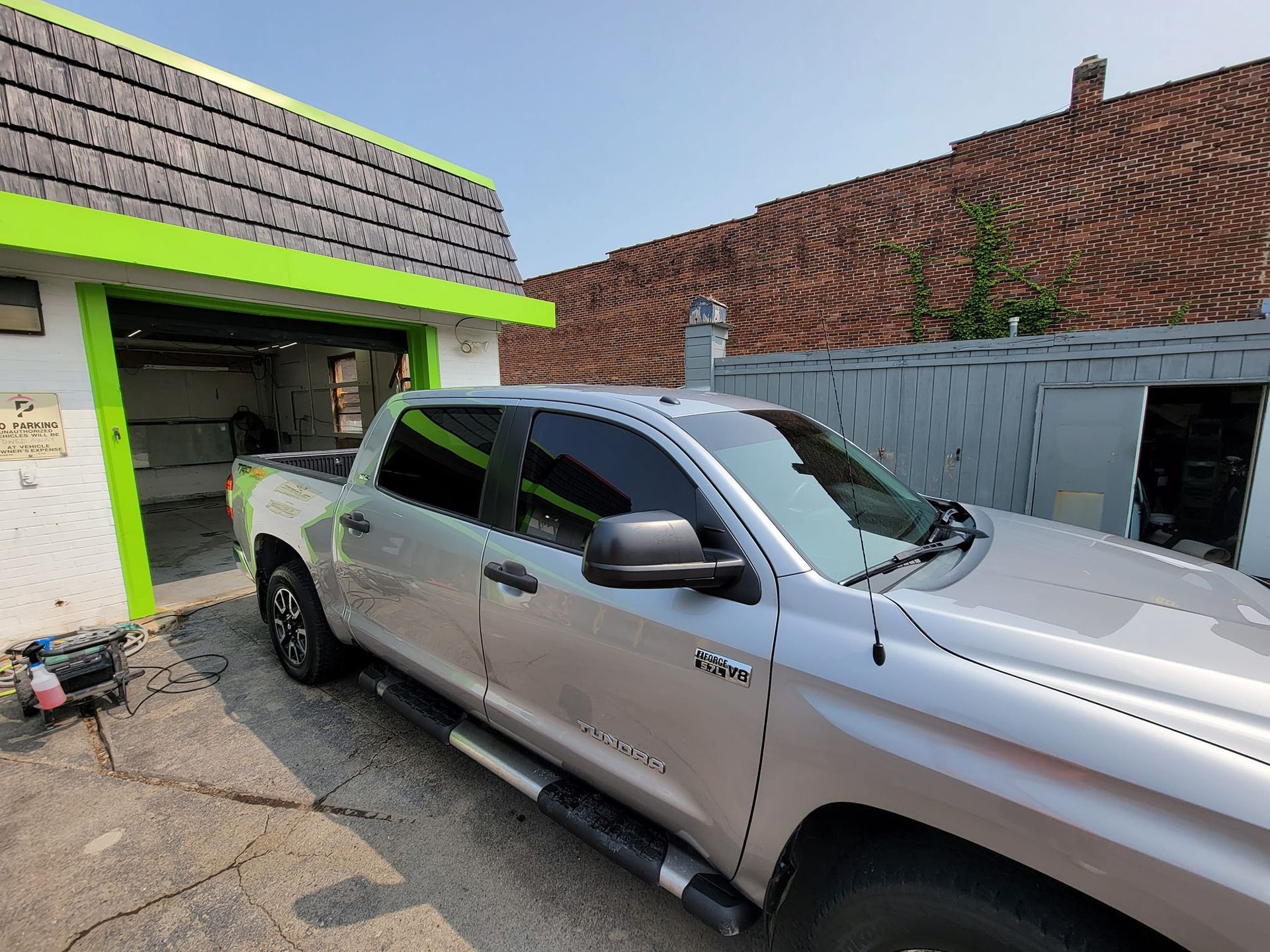 A silver truck is parked in front of a garage.