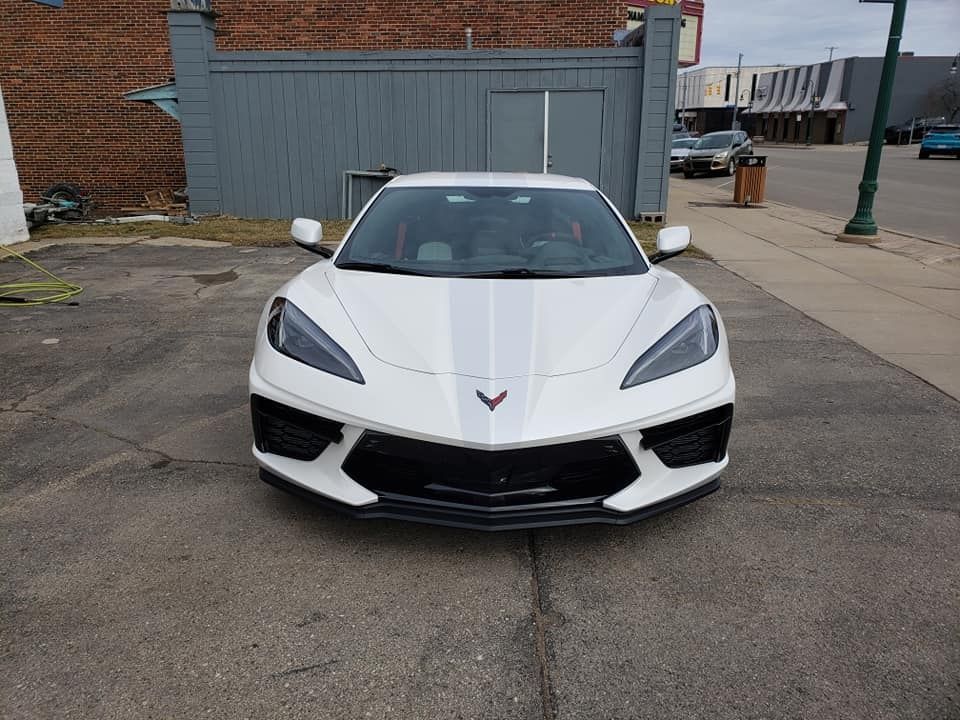 A white corvette is parked in a parking lot in front of a building.