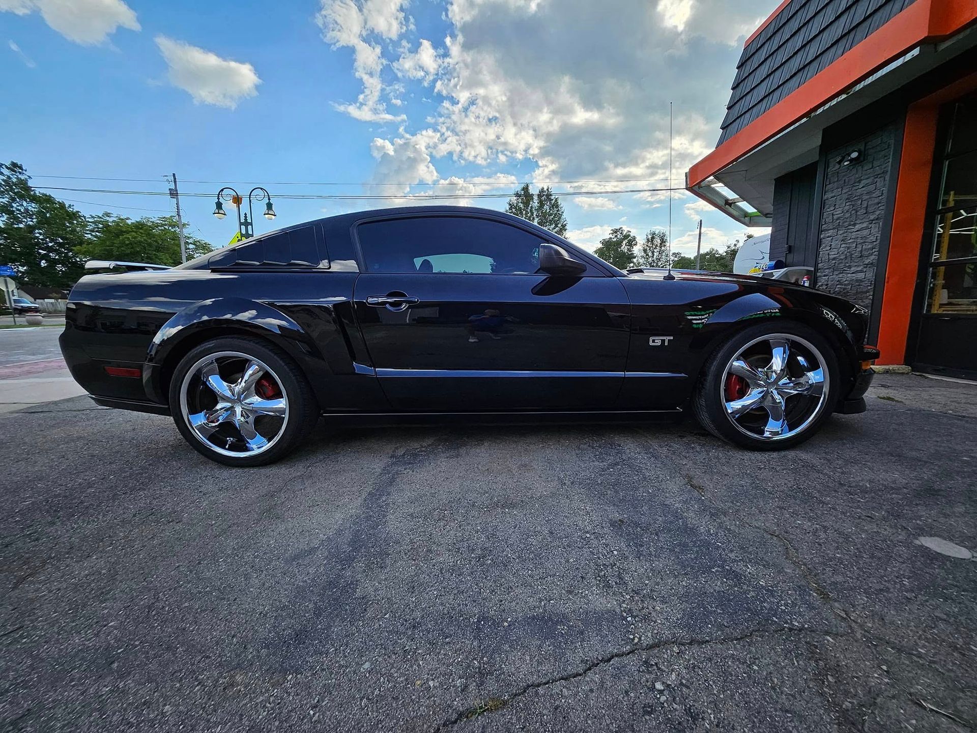 A black mustang is parked in front of a building.