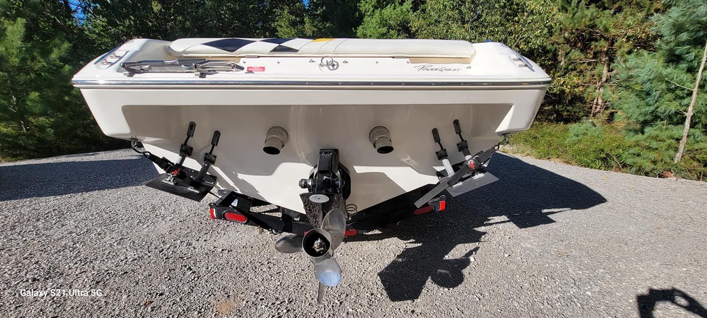 A white boat is parked on a gravel road.