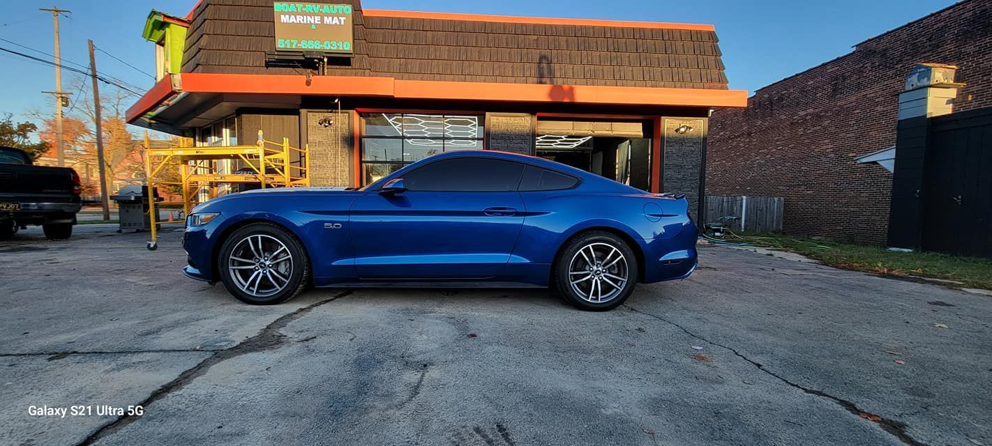 A blue mustang is parked in front of a building.