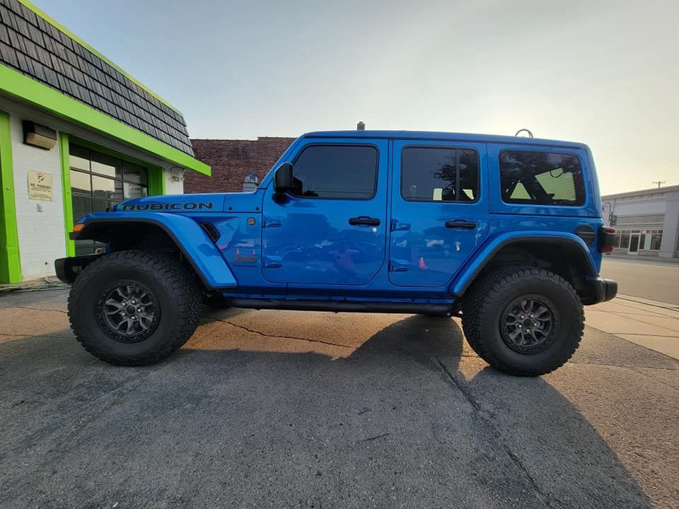 A blue jeep wrangler is parked in front of a building.
