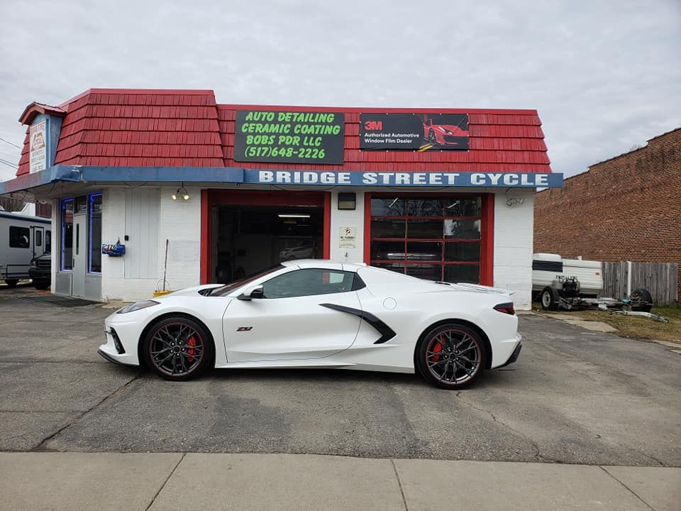 A white sports car is parked in front of a bridge street cycle shop.
