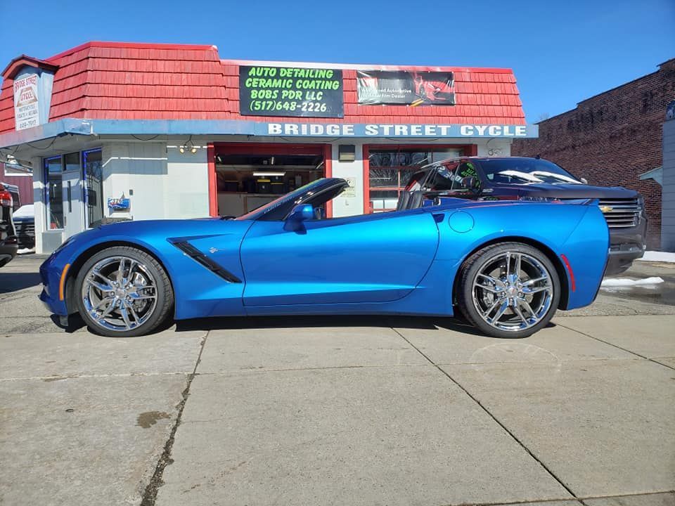 A blue sports car is parked in front of a building that says bridge street cycle