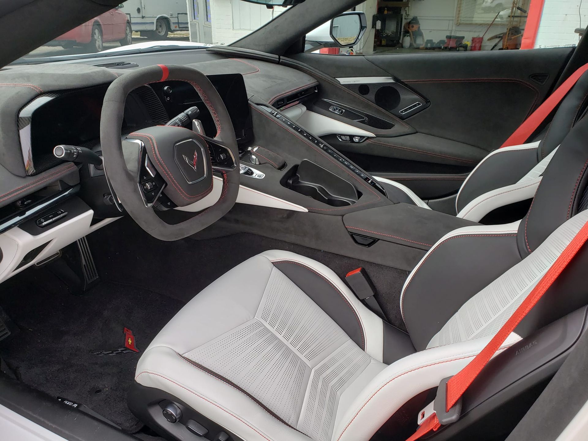 The interior of a white sports car with red seat belts