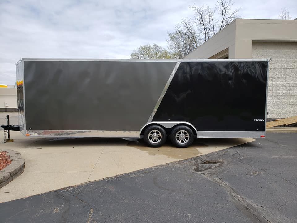 A black and silver trailer is parked in a parking lot.