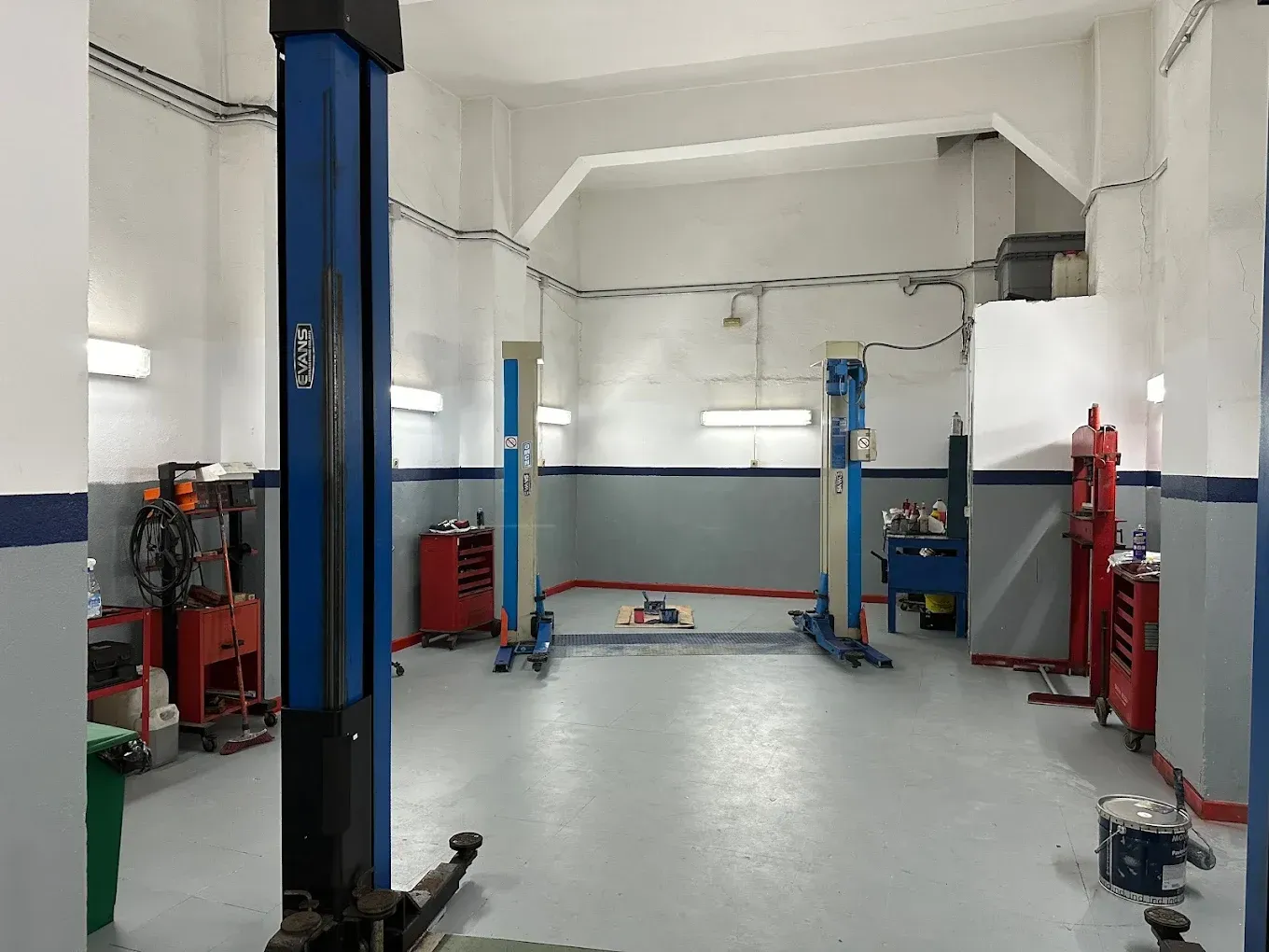 Interior de taller de reparación de automóviles con elevador de vehículos, herramientas y equipos.