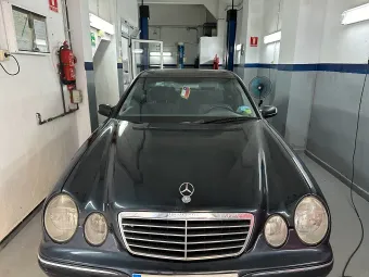 Un sedán Mercedes azul oscuro dentro de un garaje, frente a la cámara.