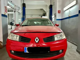Un Renault rojo en un garaje, de frente al espectador. El coche está en un elevador.