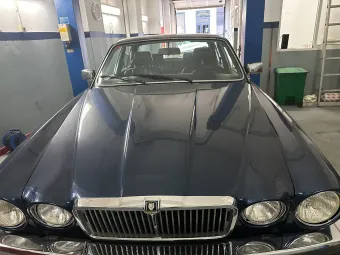 Coche Jaguar azul aparcado dentro de un garaje, mostrando su frente.