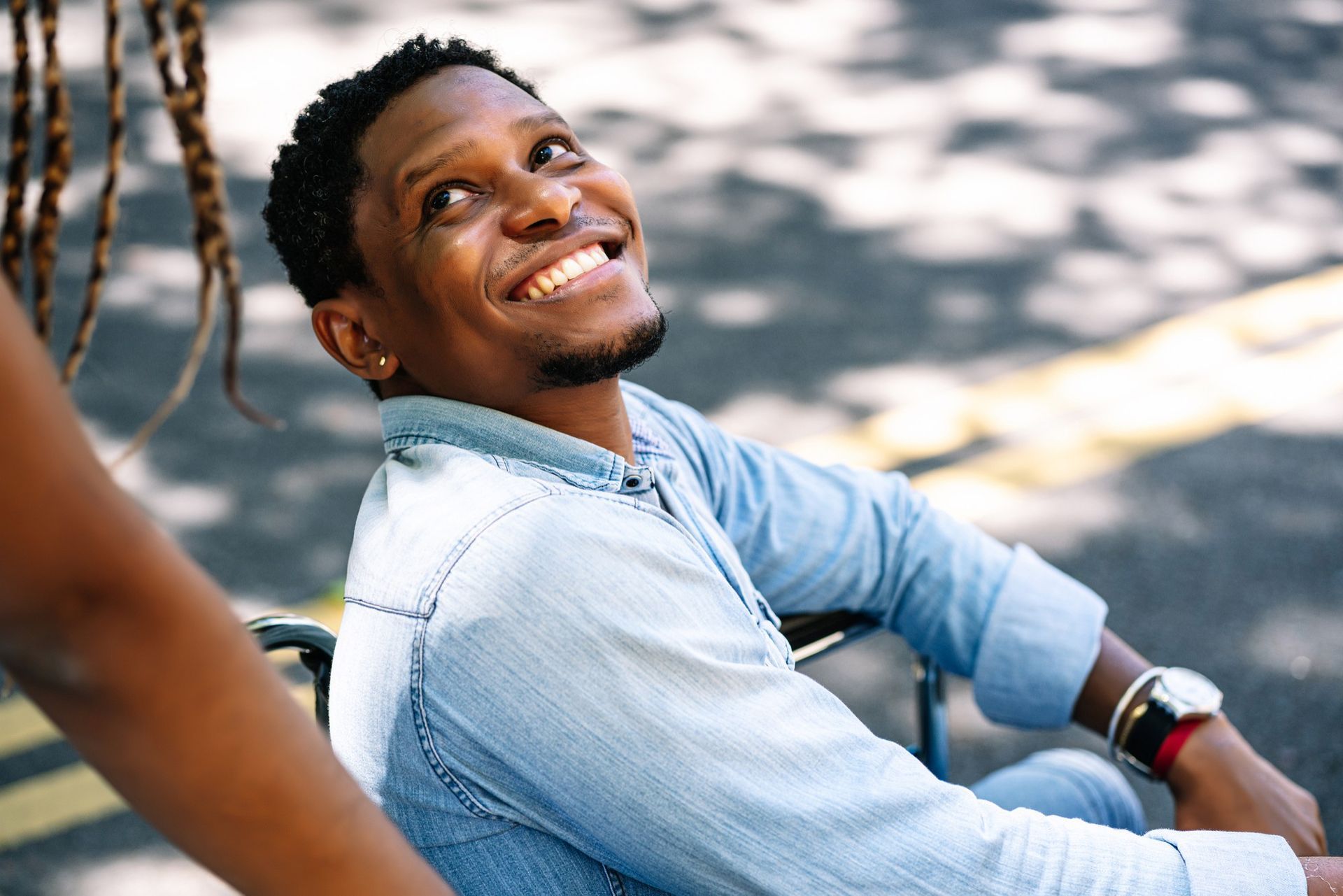 A man in a wheelchair is smiling and looking up.