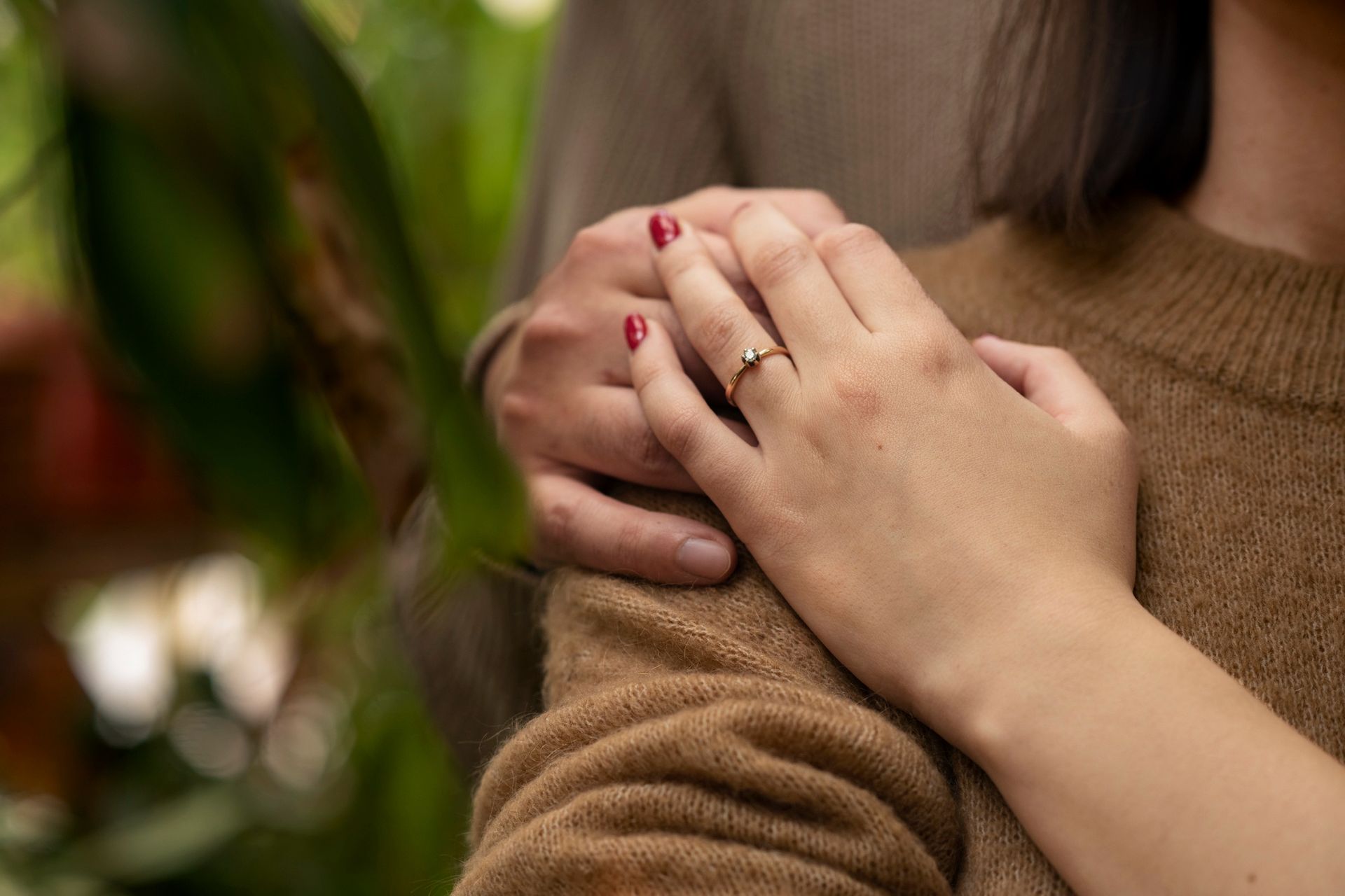 A close up of a woman 's hand with an engagement ring on it.