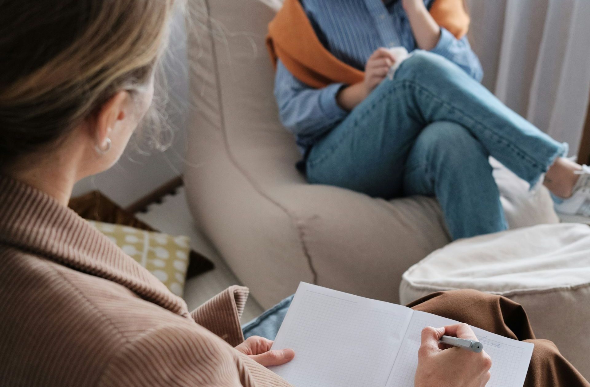 A woman is sitting in a chair talking to another woman.