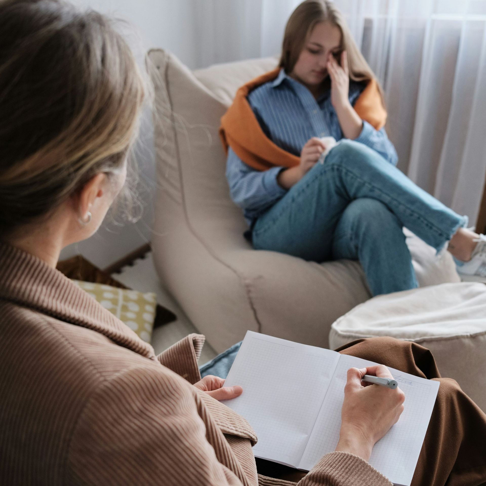 A woman is sitting in a bean bag chair talking to another woman.
