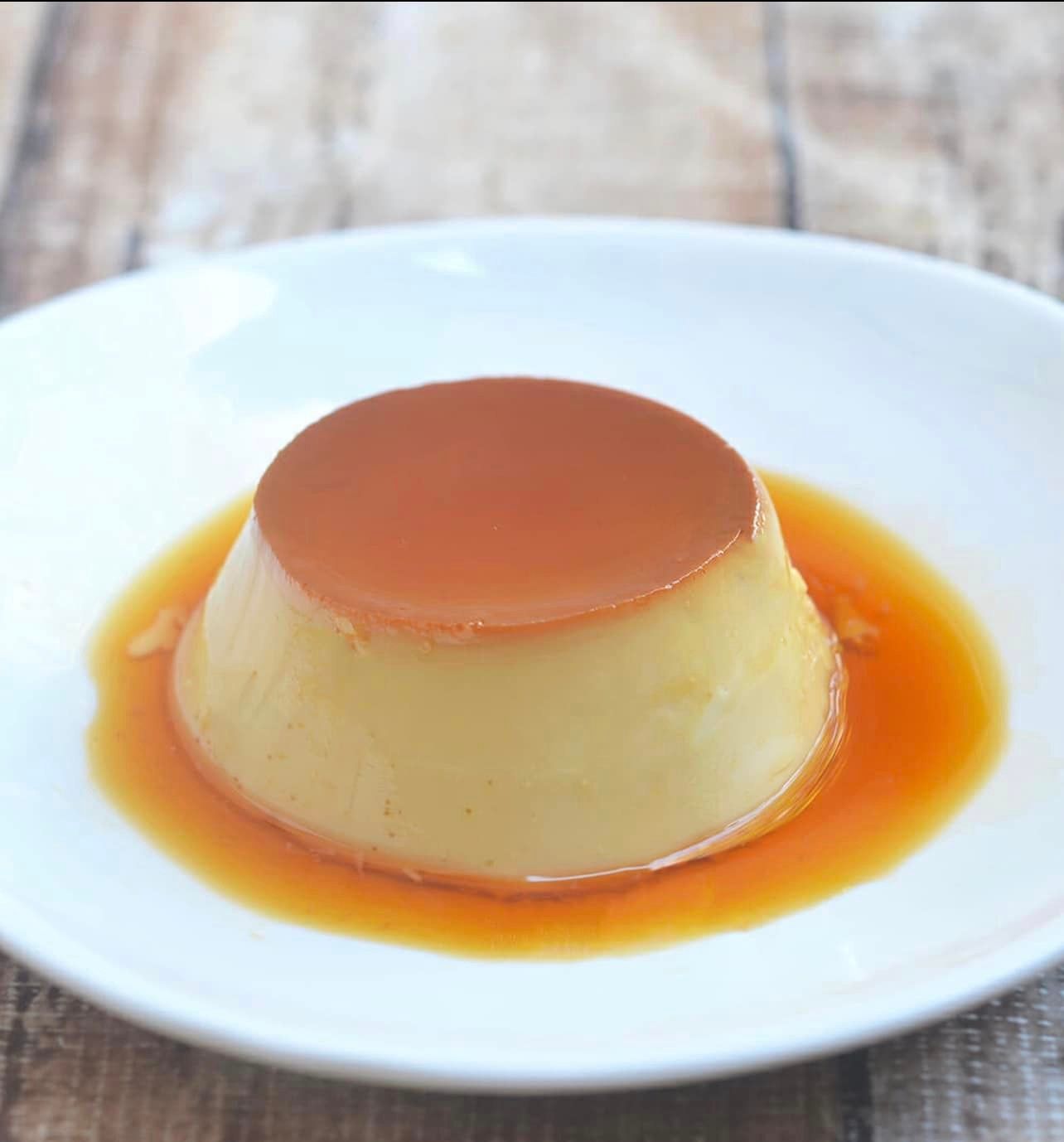A white plate topped with a pudding and caramel sauce