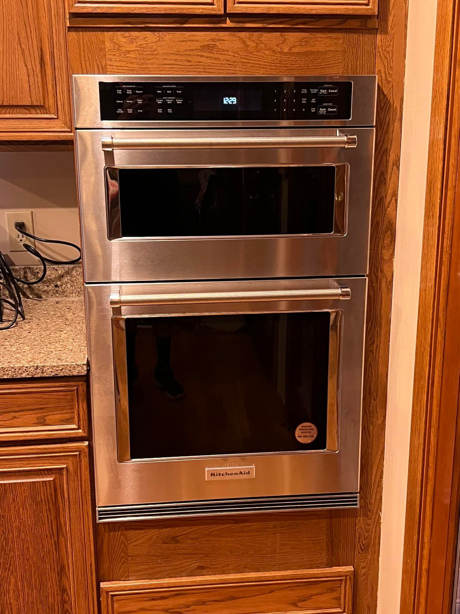 Stainless steel double oven built into a wooden cabinet with a digital display.