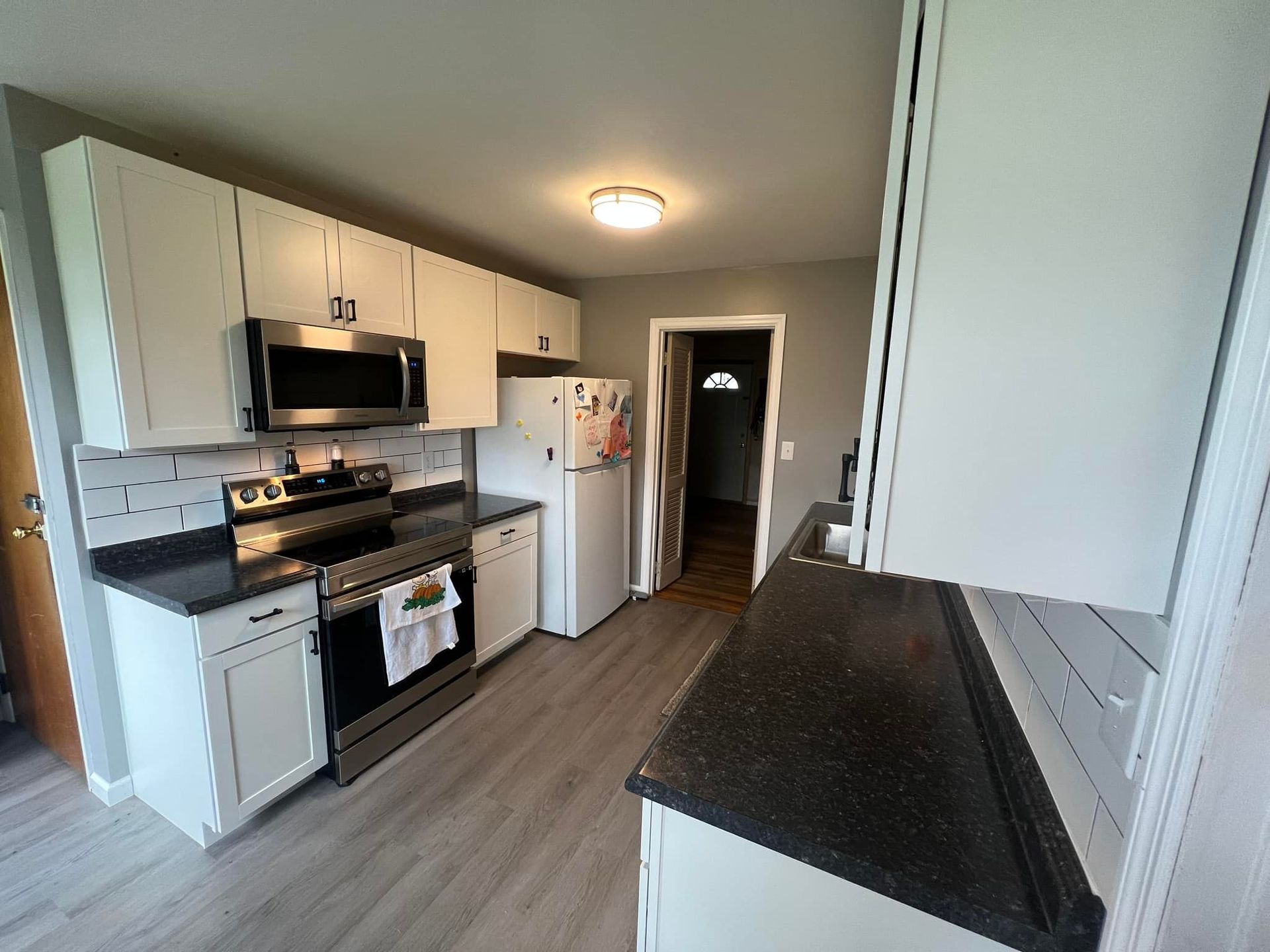 Kitchen with white cabinets, stainless steel appliances, and dark countertops.
