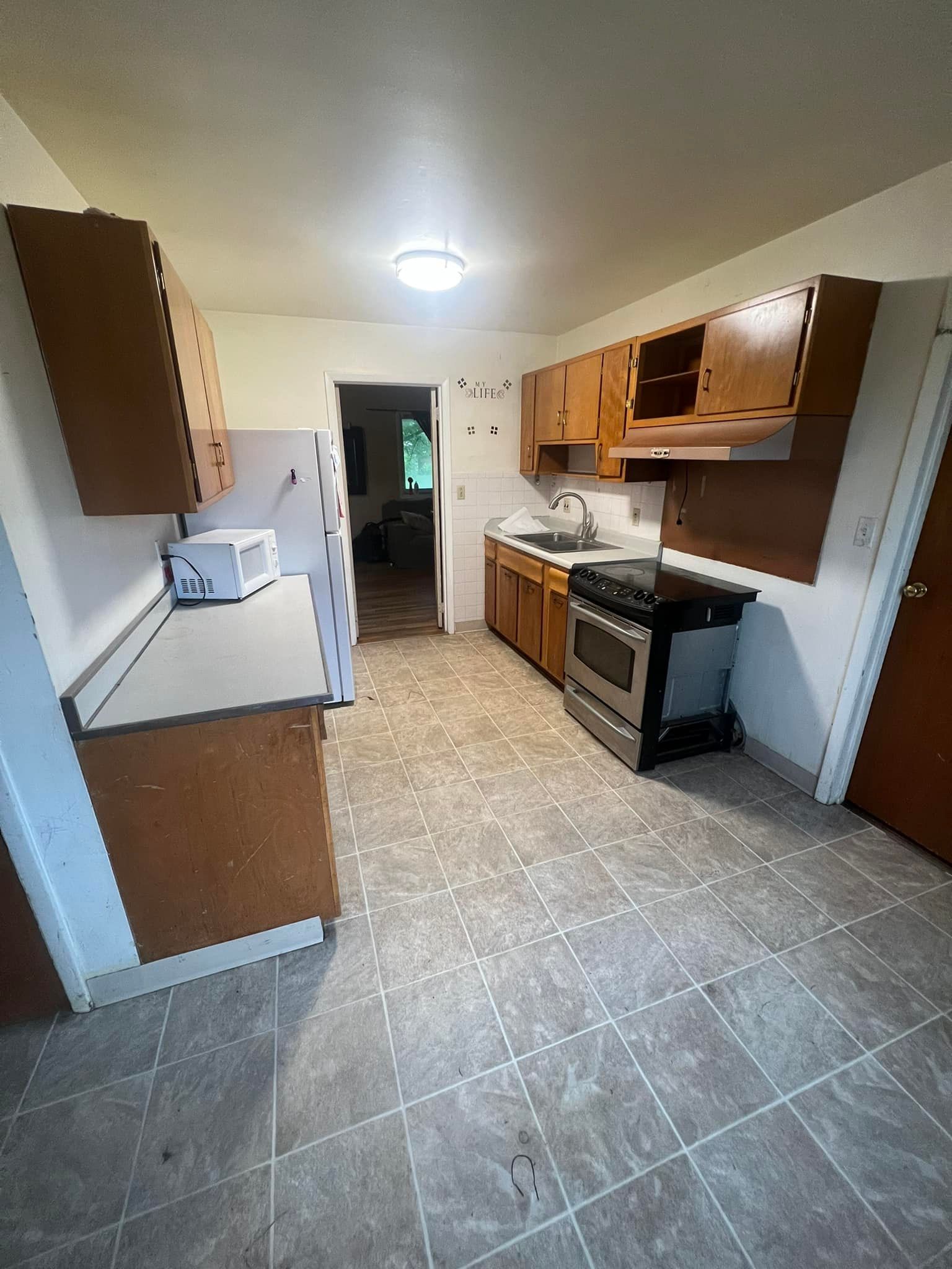 Kitchen with wooden cabinets, stainless steel stove, and white refrigerator.