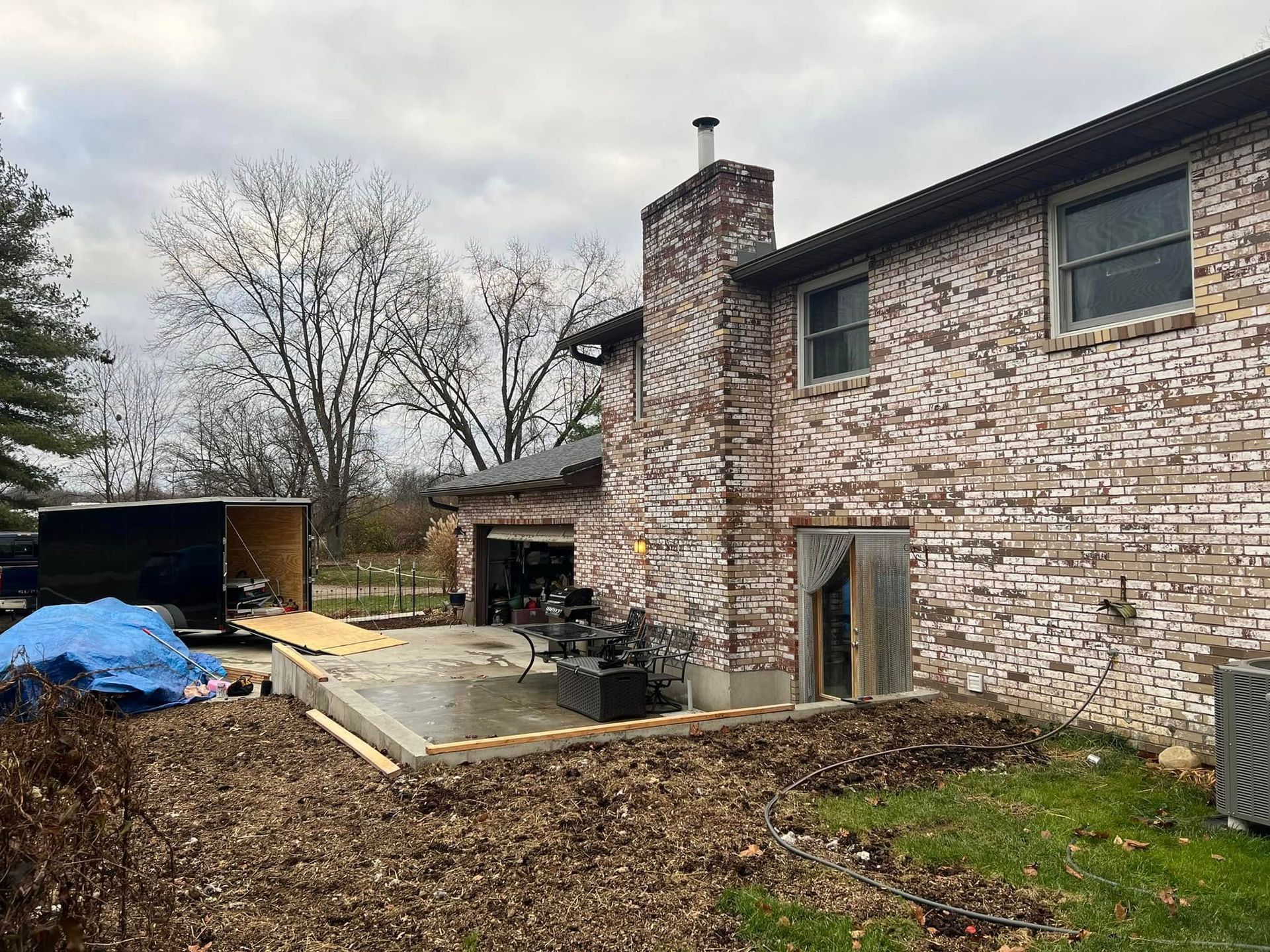 Brick house with a newly poured concrete patio, construction in progress.