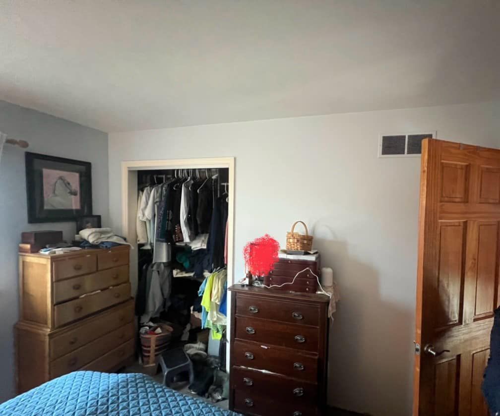 Bedroom with a wooden closet, dresser, and blue bed.