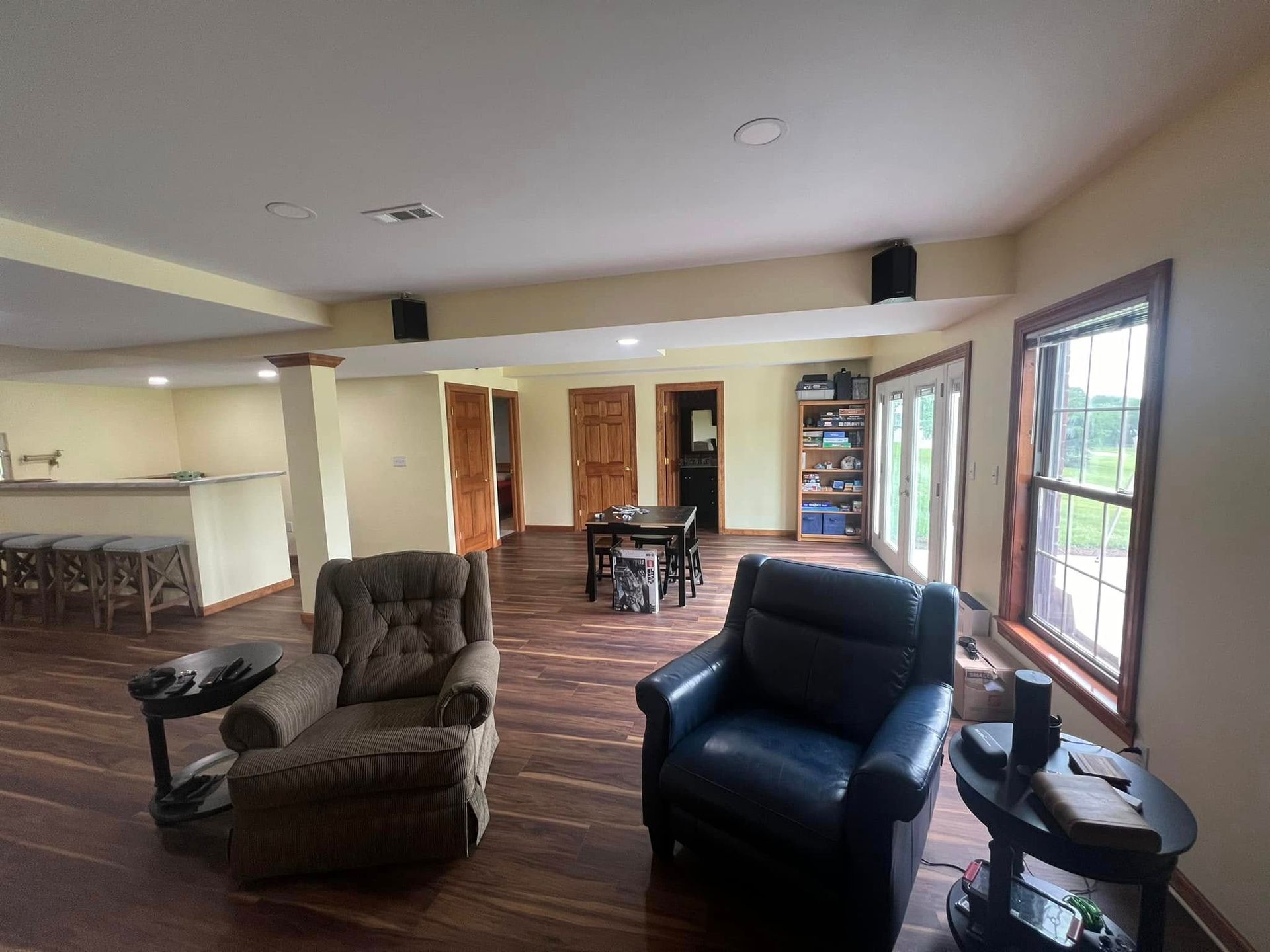 Spacious living room with hardwood floors, two armchairs, a table, and a set of glass doors.
