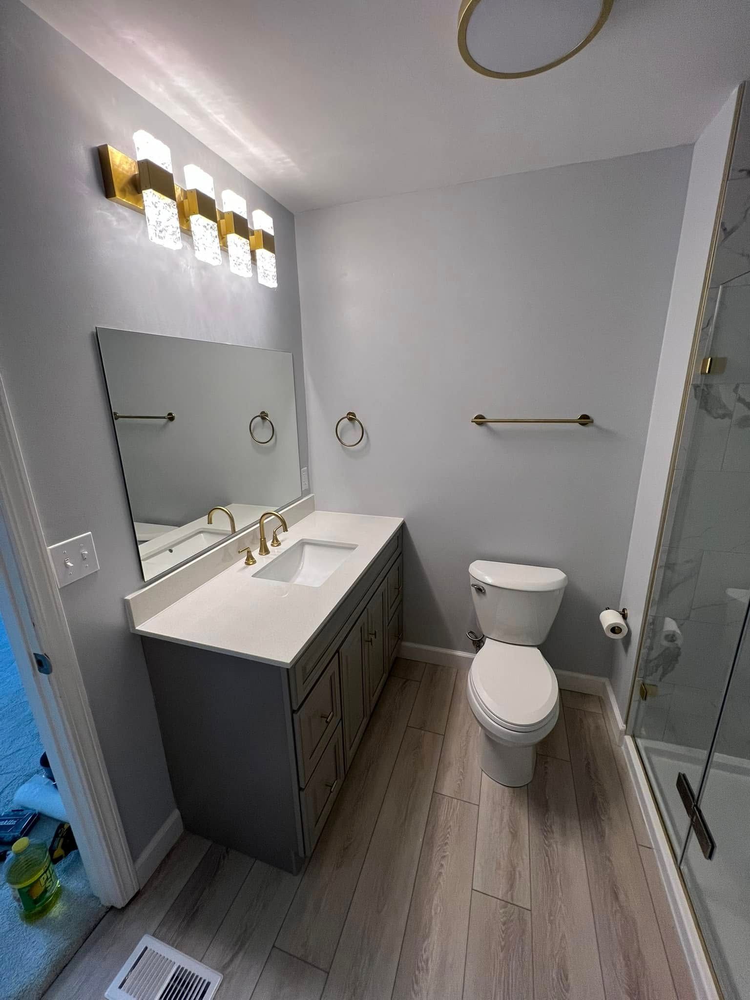 Modern bathroom with gray vanity, white countertop, and light blue walls.