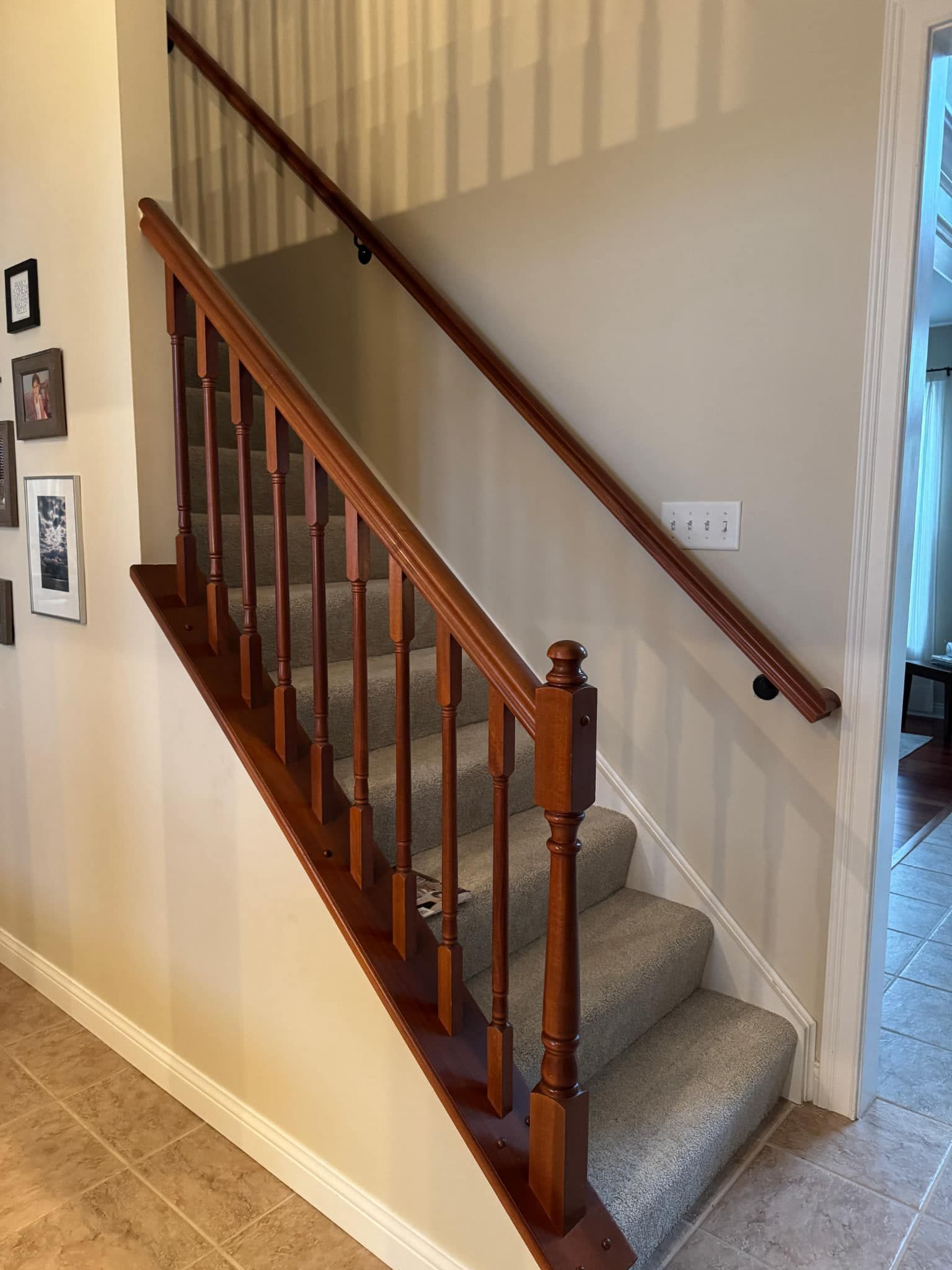 Staircase with wooden handrails and carpeted steps against tan walls.