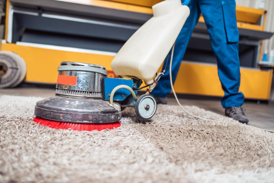 A man is cleaning a carpet with a machine.