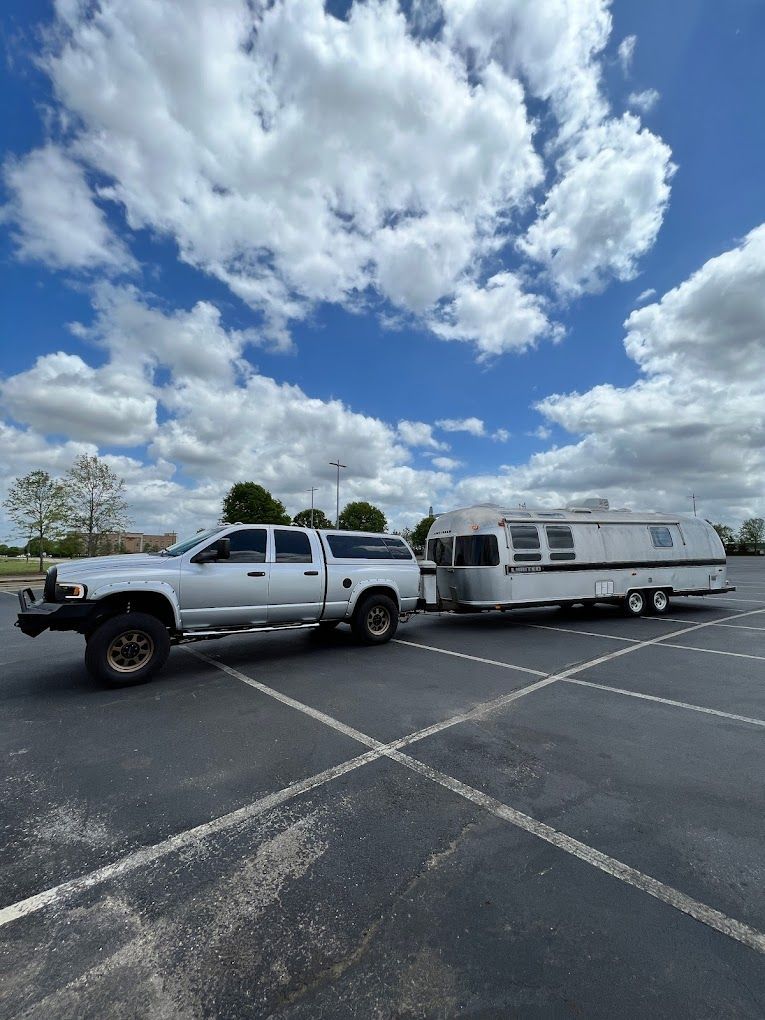 A truck is towing a trailer in a parking lot
