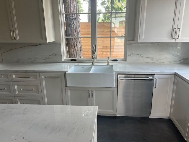 A plumber is fixing a sink in a bathroom while a woman looks on.