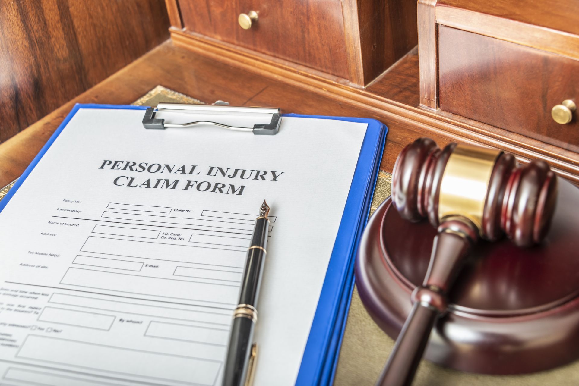 Personal injury claim form on clipboard beside a judge’s gavel on a desk